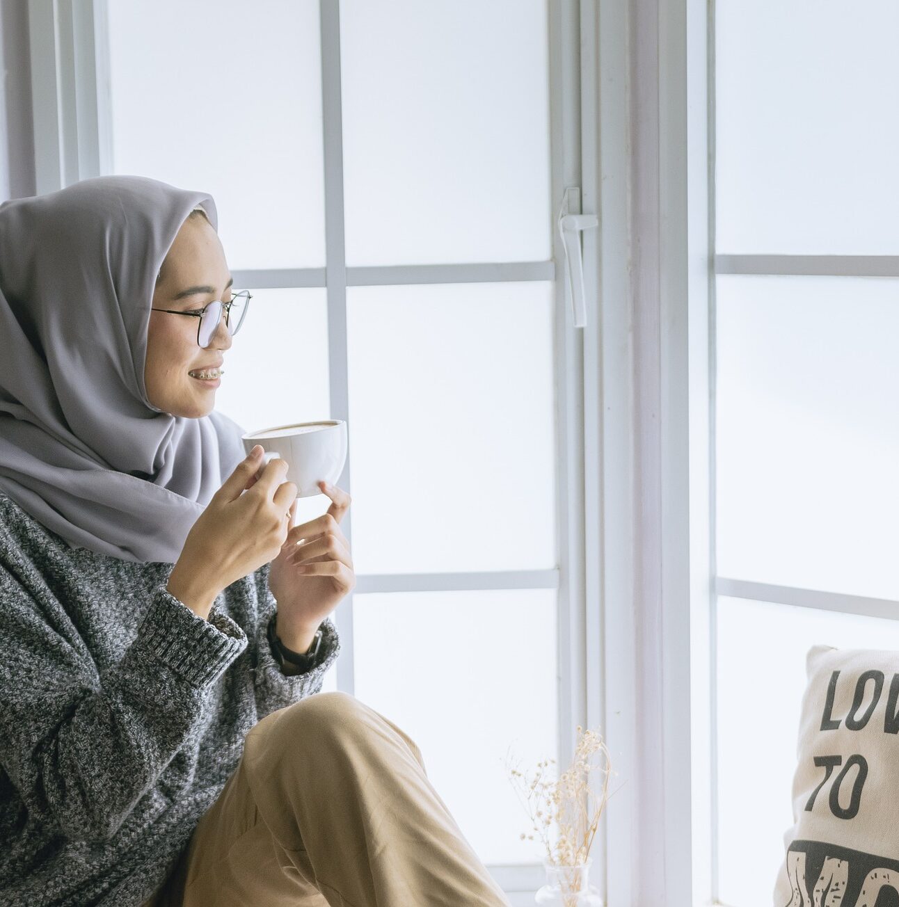 woman sitting by a window with a cup of tea