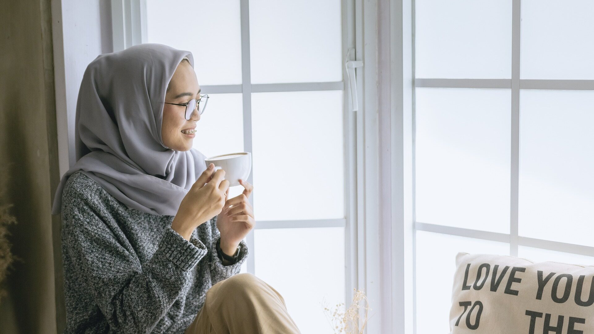 woman sitting by a window with a cup of tea