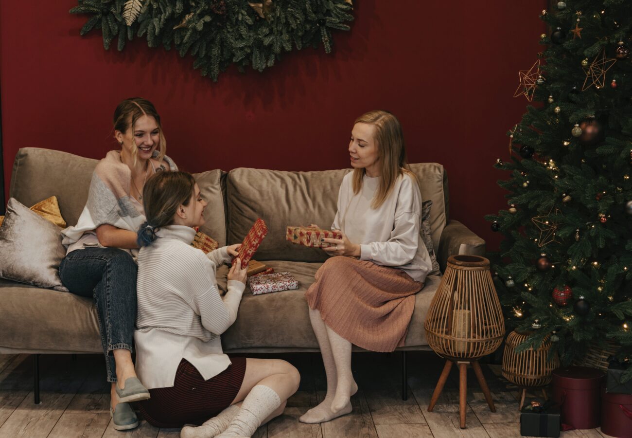 three friends sitting by a Christmas tree