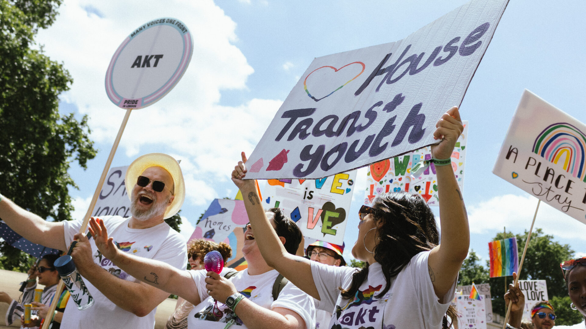 A group of akt staff and volunteers at Pride in London's parade 2026. An akt staff member is holding a placard that says 