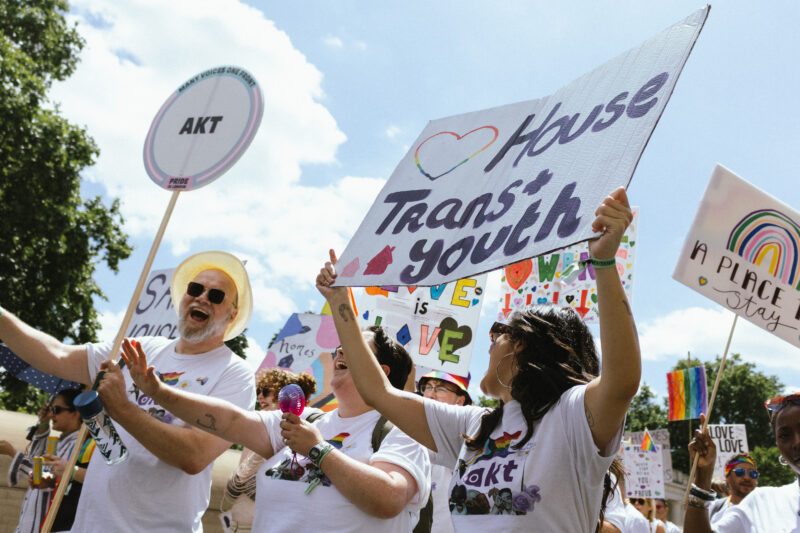 A group of akt staff and volunteers at Pride in London's parade 2026. An akt staff member is holding a placard that says 